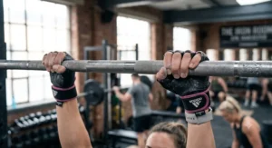 Female lifter demonstrating callus protection while using weightlifting gloves on a pull-up bar