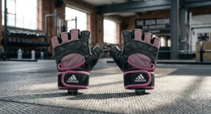 Pair of lightweight pink and black weightlifting gloves for women laid flat on a gym mat