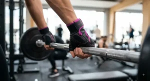Close-up of non-slip leather women's gym gloves gripping a heavy barbell in a modern gym