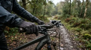 A rider wearing the best budget MTB gloves on a muddy woodland trail