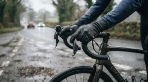Commuter cycling gloves being worn in a rainy city street setting with puddles on the pavement.