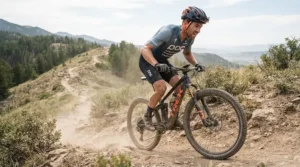 Mountain biker climbing a steep gravel track wearing flexible trail gloves for hot weather